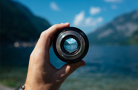 A view of a lake as seen through a camera lens being held in a person's hand