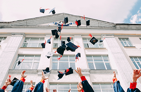 Students celebrating graudation by throwing their hats in the air