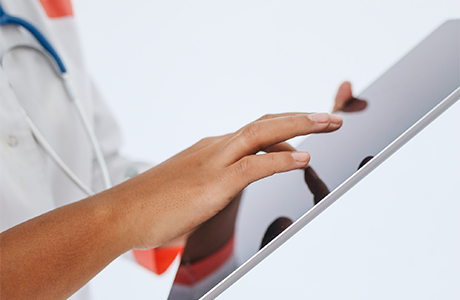 A person wearing a stethoscope and using a tablet computer