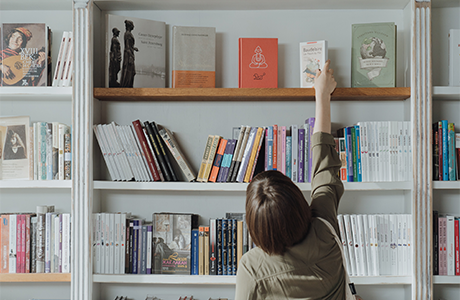 A person reaching for a book on shelf