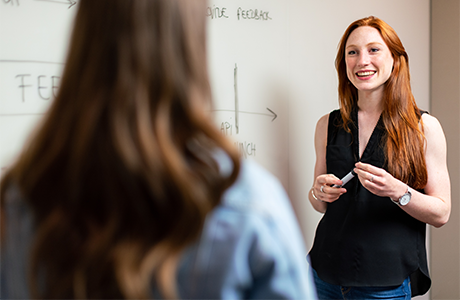 Female instructor smiling in front of a white board