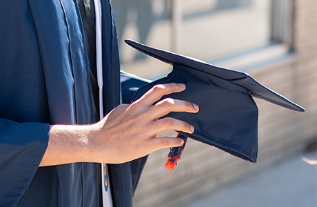 Close up image of individual holding a graduation cap 