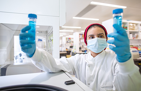 Woman in a lab observing test tubes 