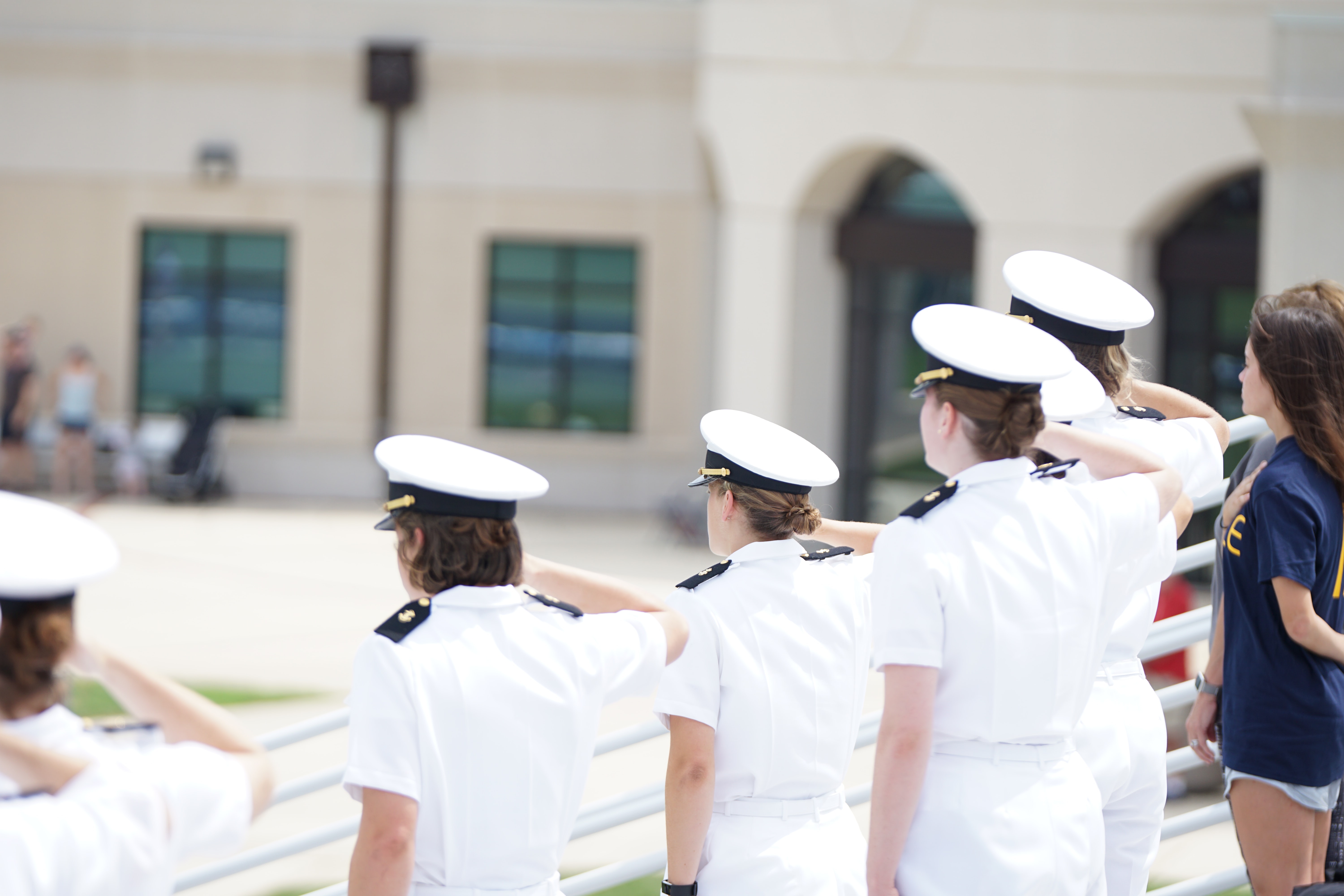 Group of people in white costum standing and saluting.