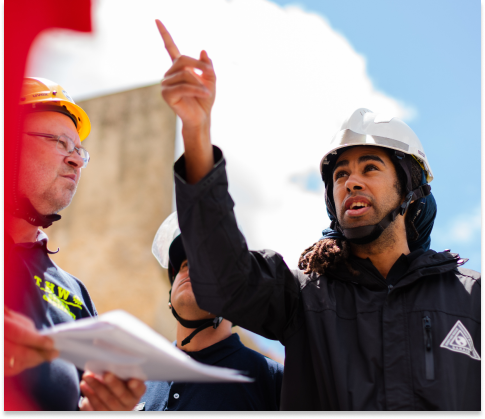man with a construction helmet pointing at a construction 